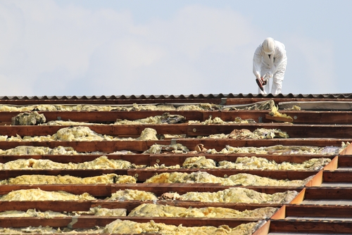 Employee of an emergency restoration services company on a roof removing harmful asbestos