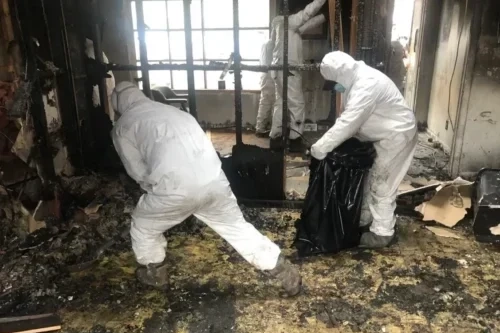 Workers from disaster recovery services company in hazmat suits cleaning out fire damaged home