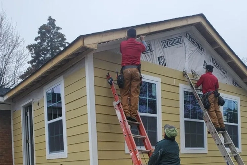 construction crew from disaster recovery services company restoring outside of home after fire damage