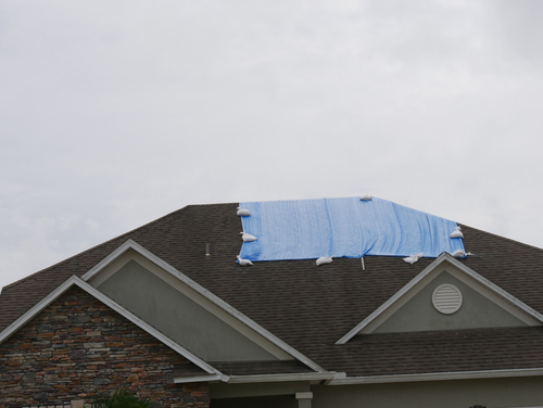 damaged roof being tarped up by an emergency restoration services companu